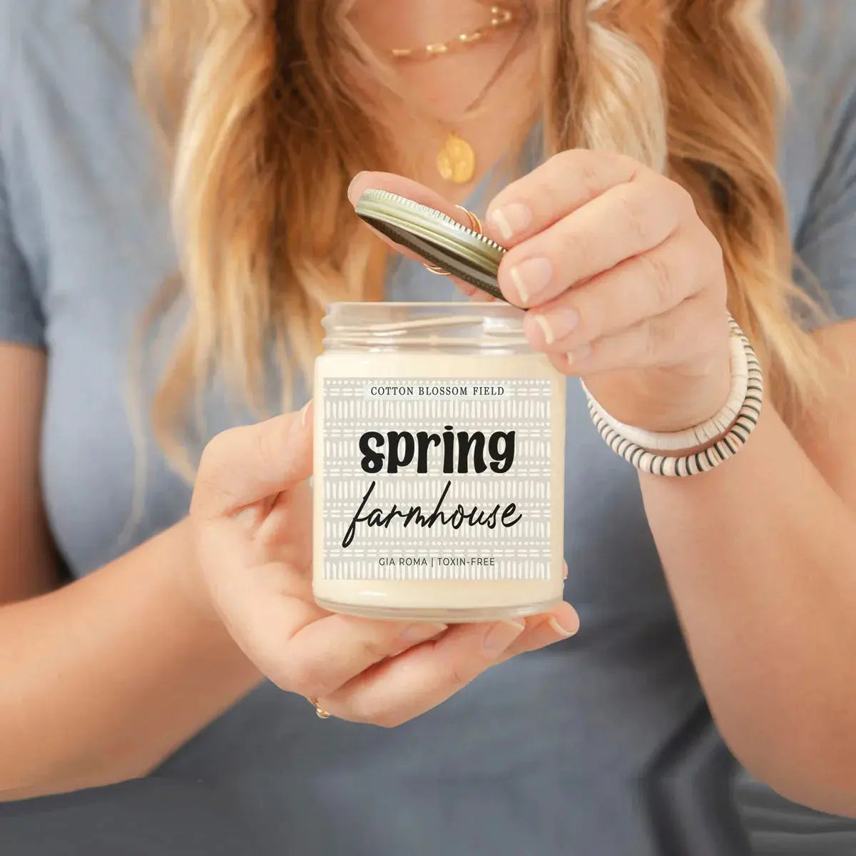 Person holding a candle labeled 'Spring Cleaning' with a neutral background