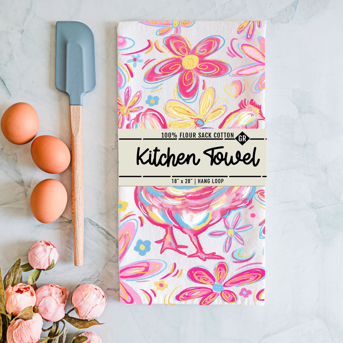 Floral patterned kitchen towel with a spatula and eggs on a marble surface