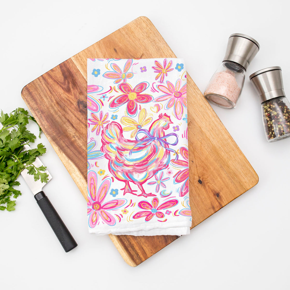 Colorful towel with floral and rooster design on a wooden cutting board.