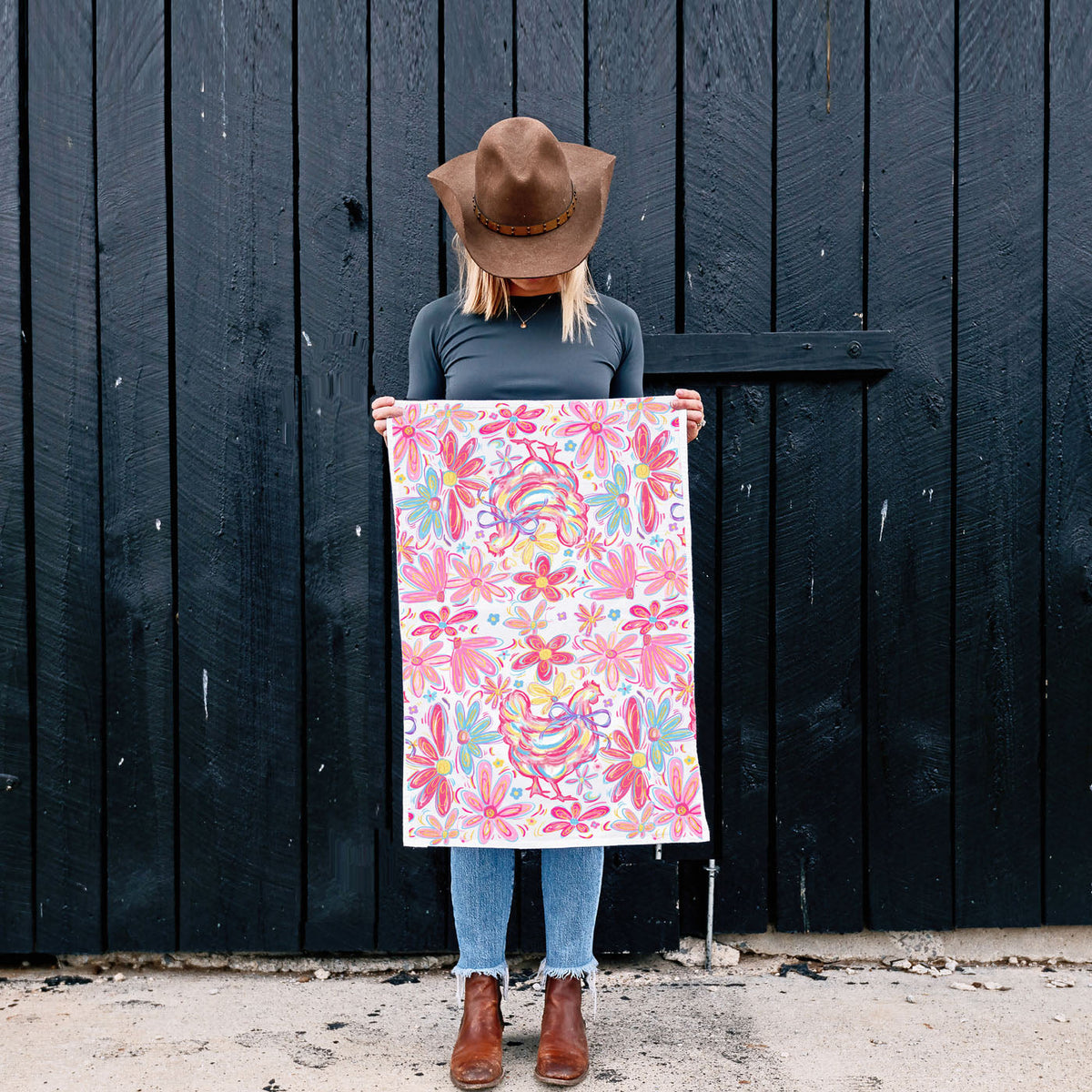 Person holding a colorful floral patterned towel against a dark wooden wall.