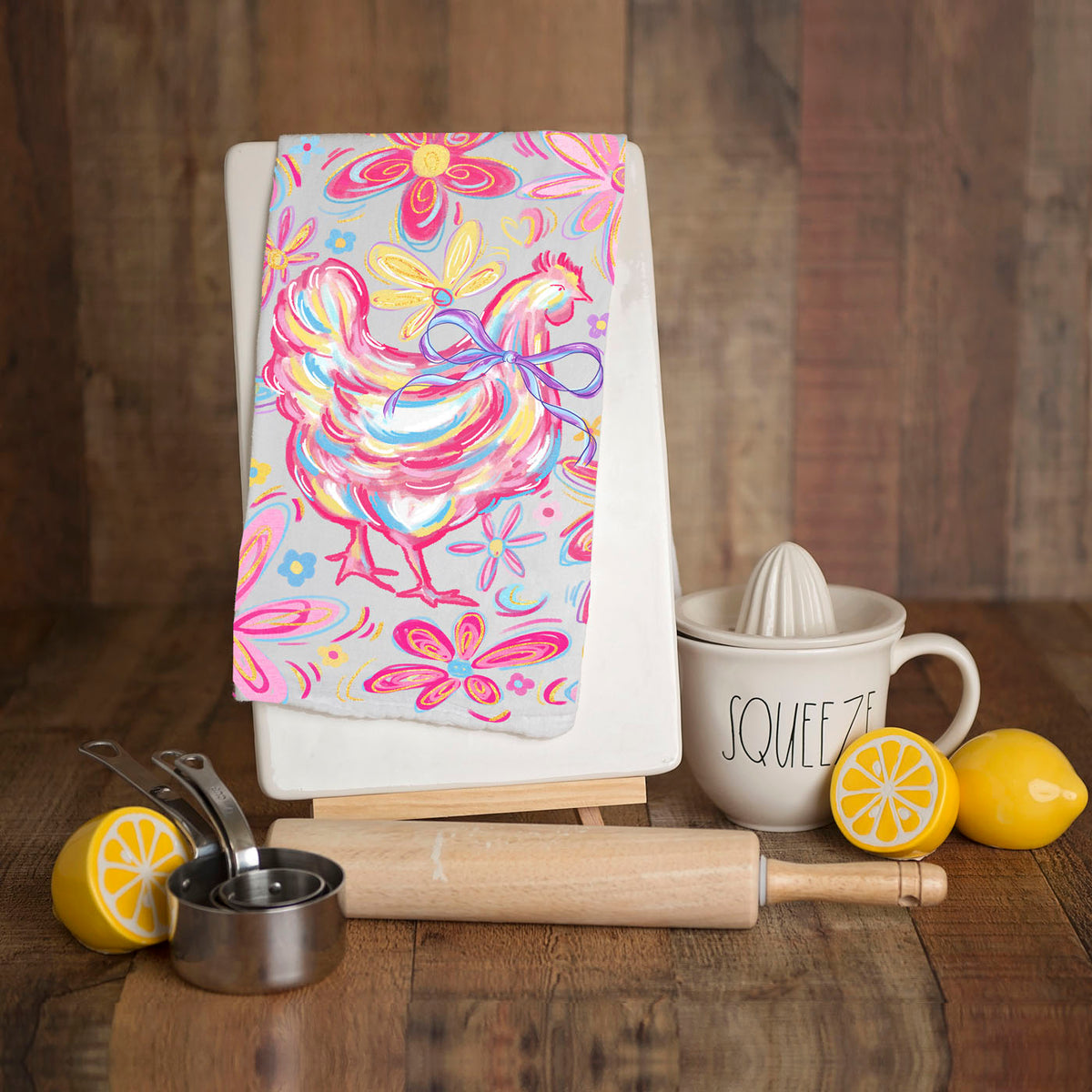 Colorful towel with rooster design on a wooden stand, surrounded by kitchen items.