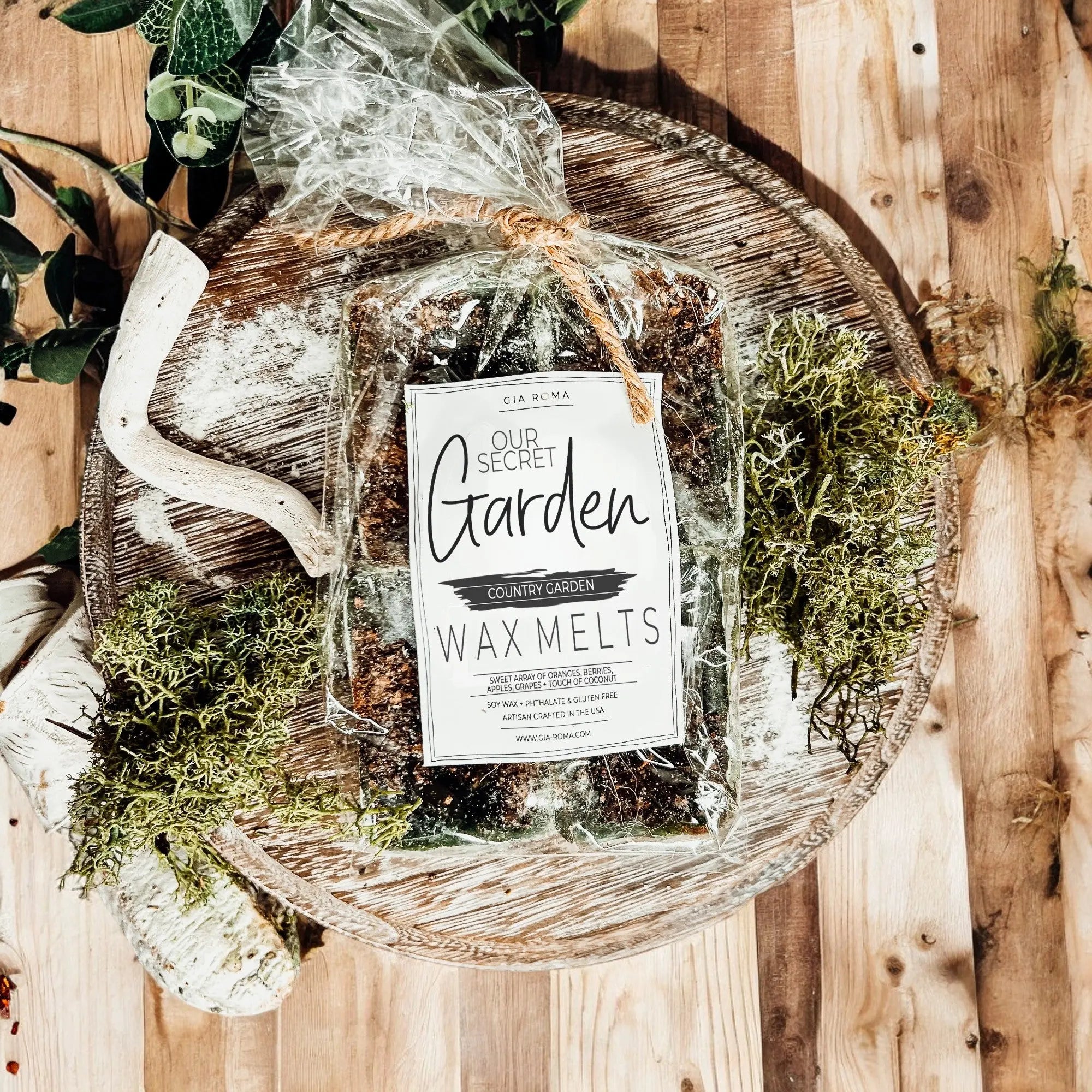 Packaged wax melts labeled 'Our Secret Garden' on a wooden surface with greenery.