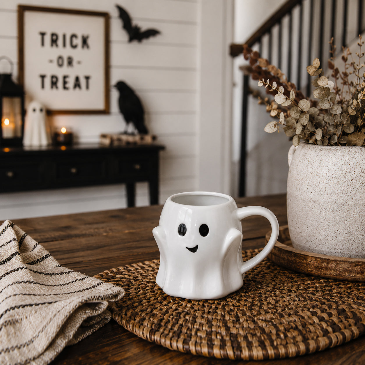 Ghost-shaped mug on a wooden table with Halloween decorations in the background