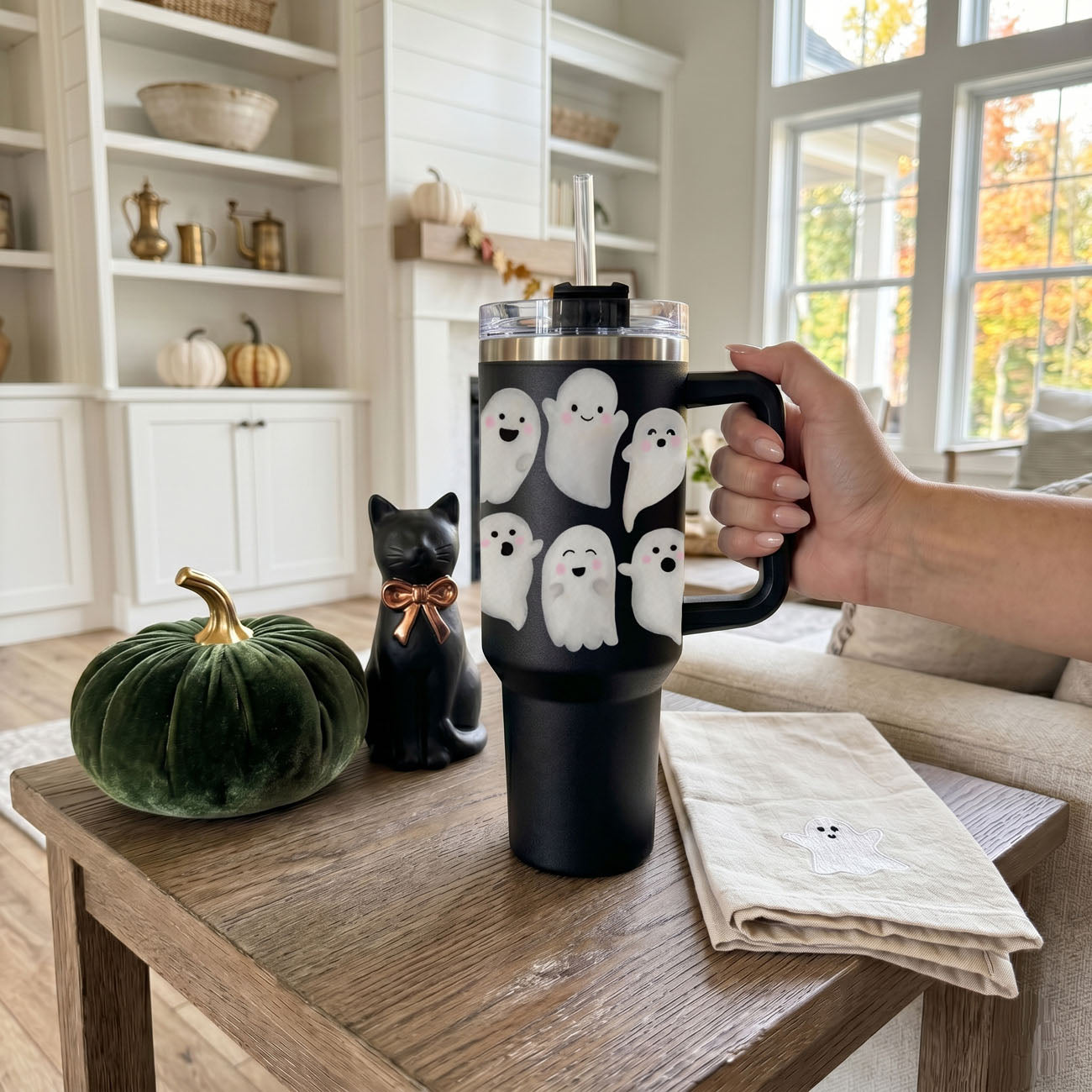 Black mug with ghost design held by a hand in a cozy living room.