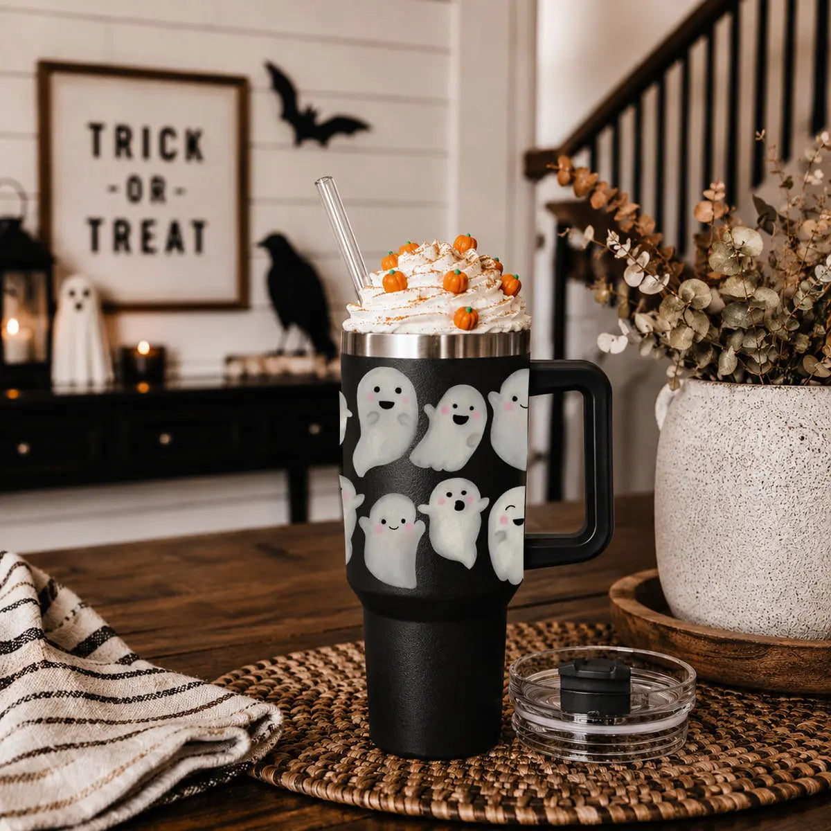 Black mug with ghost pattern on a table with Halloween decorations in the background