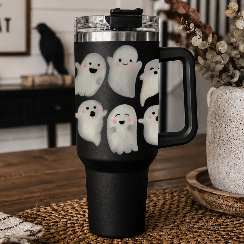 Black travel mug with ghost designs on a wooden surface