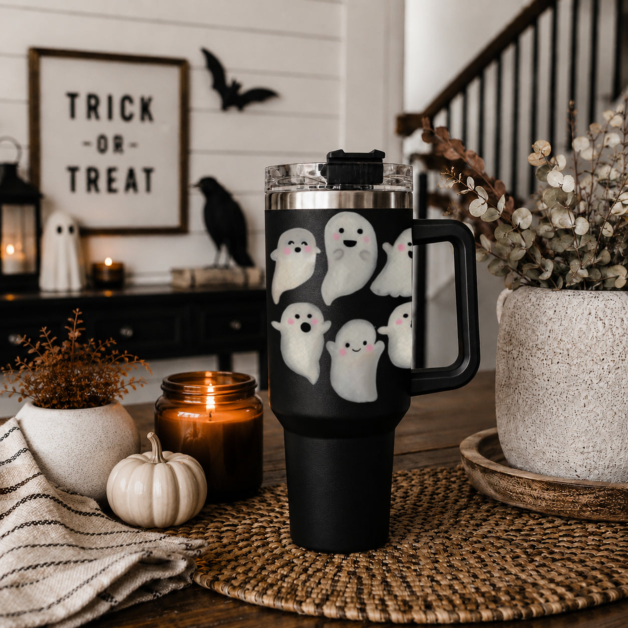 Black tumbler with ghost design on a table with Halloween decorations