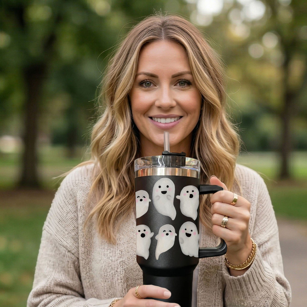 Woman holding a black mug with ghost designs outdoors