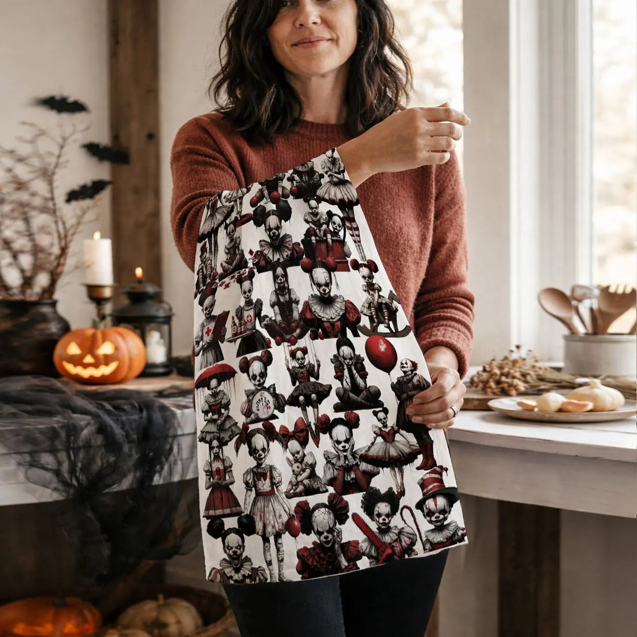 Person holding a Halloween-themed kitchen towel  in a kitchen setting with pumpkins and candles.
