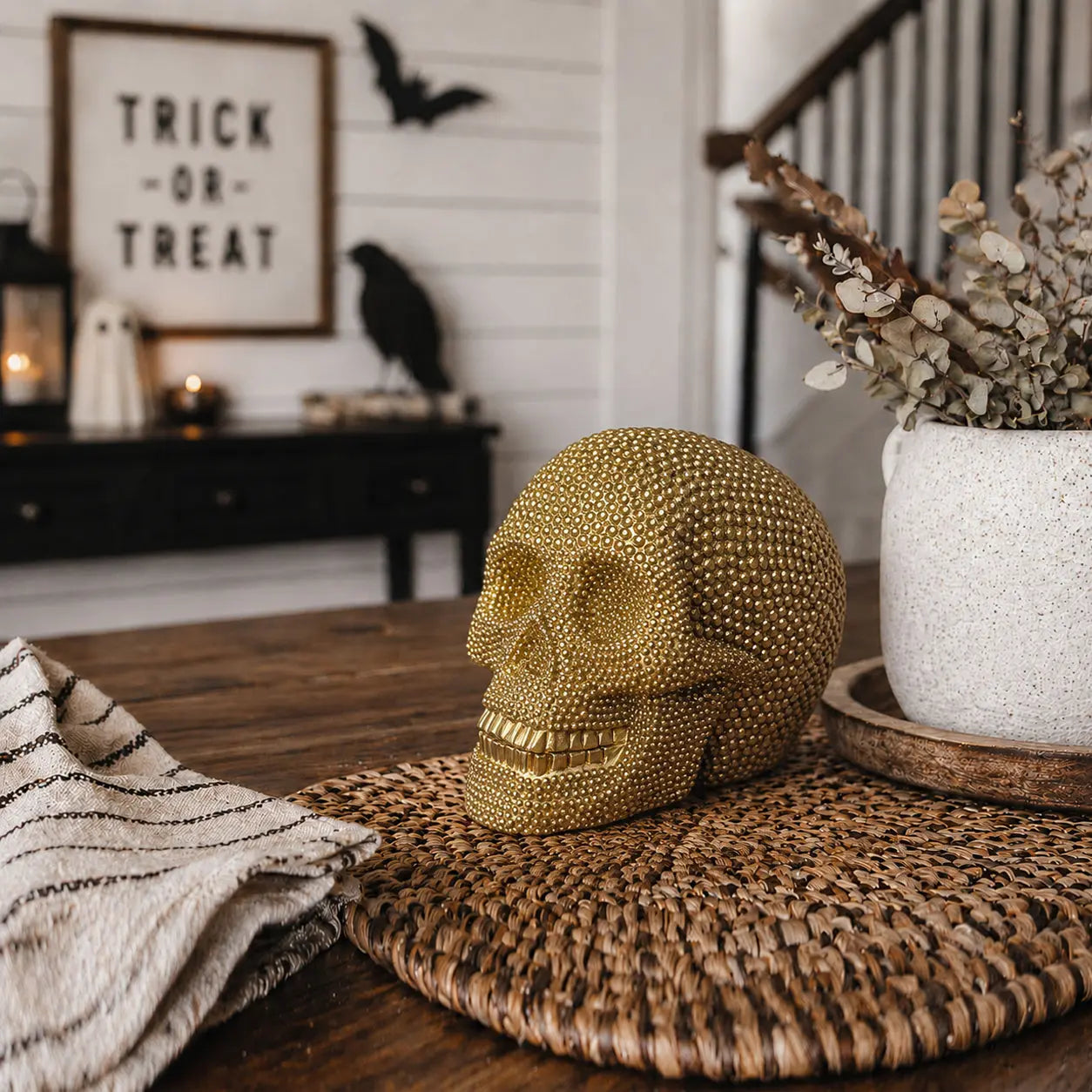 Decorative gold skull on a table with Halloween-themed decorations in the background.