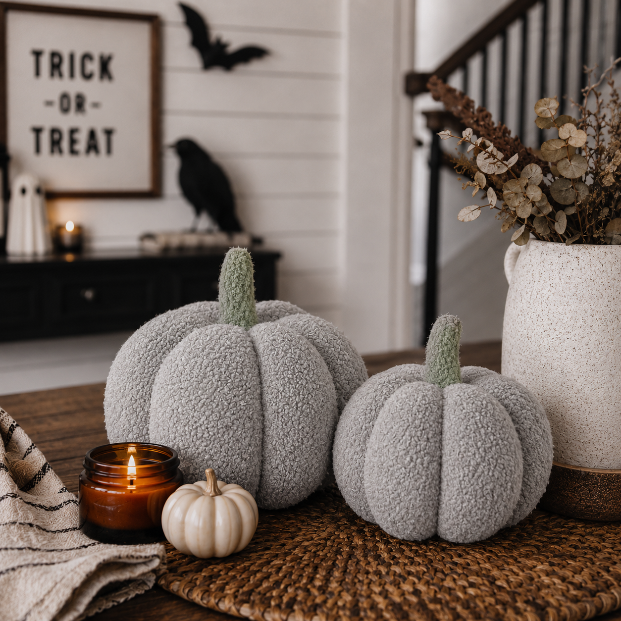 Decorative pumpkins on a table with a 'Trick or Treat' sign and Halloween decorations in the background.