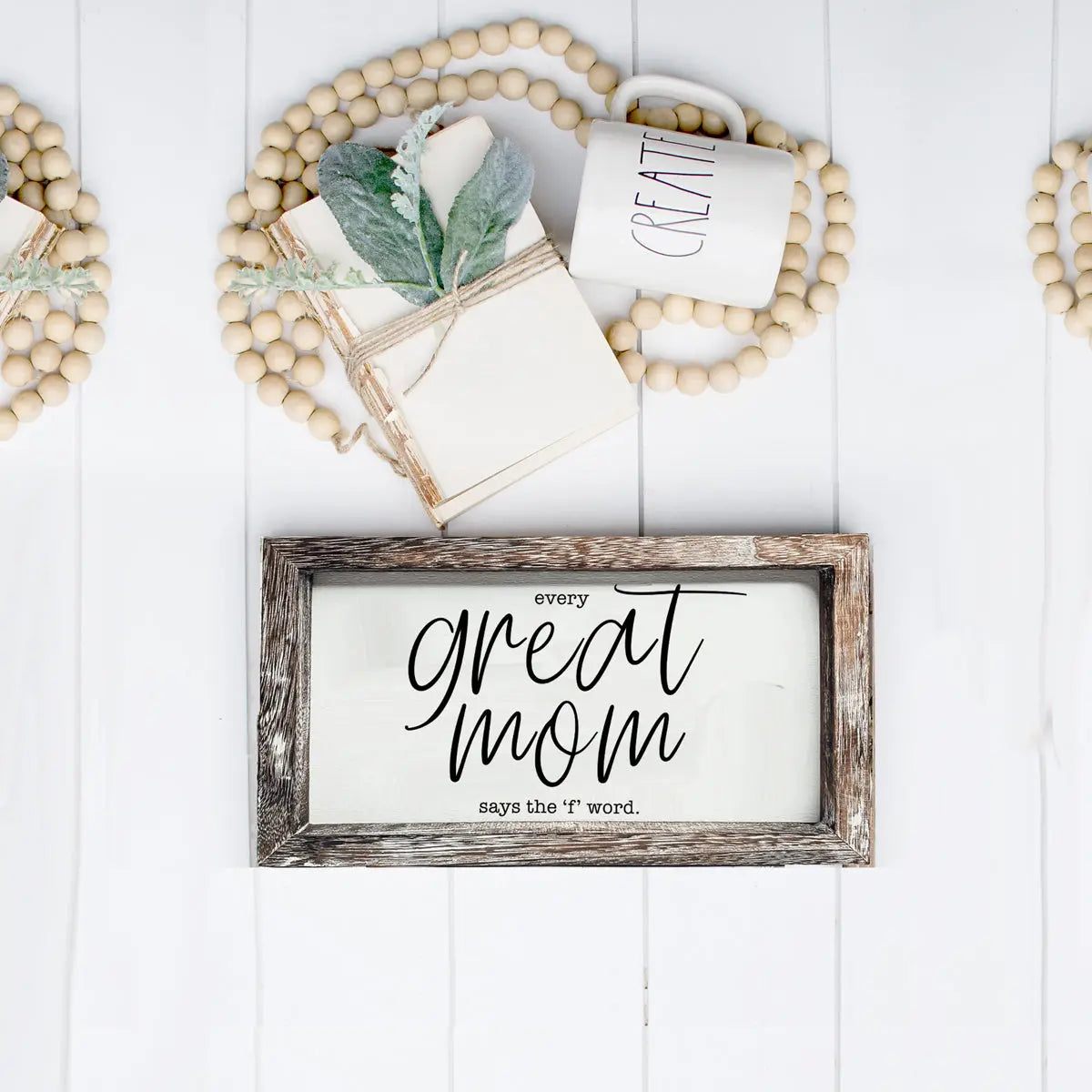 Decorative sign with 'Every Great Mom says the f word' on a white wooden background