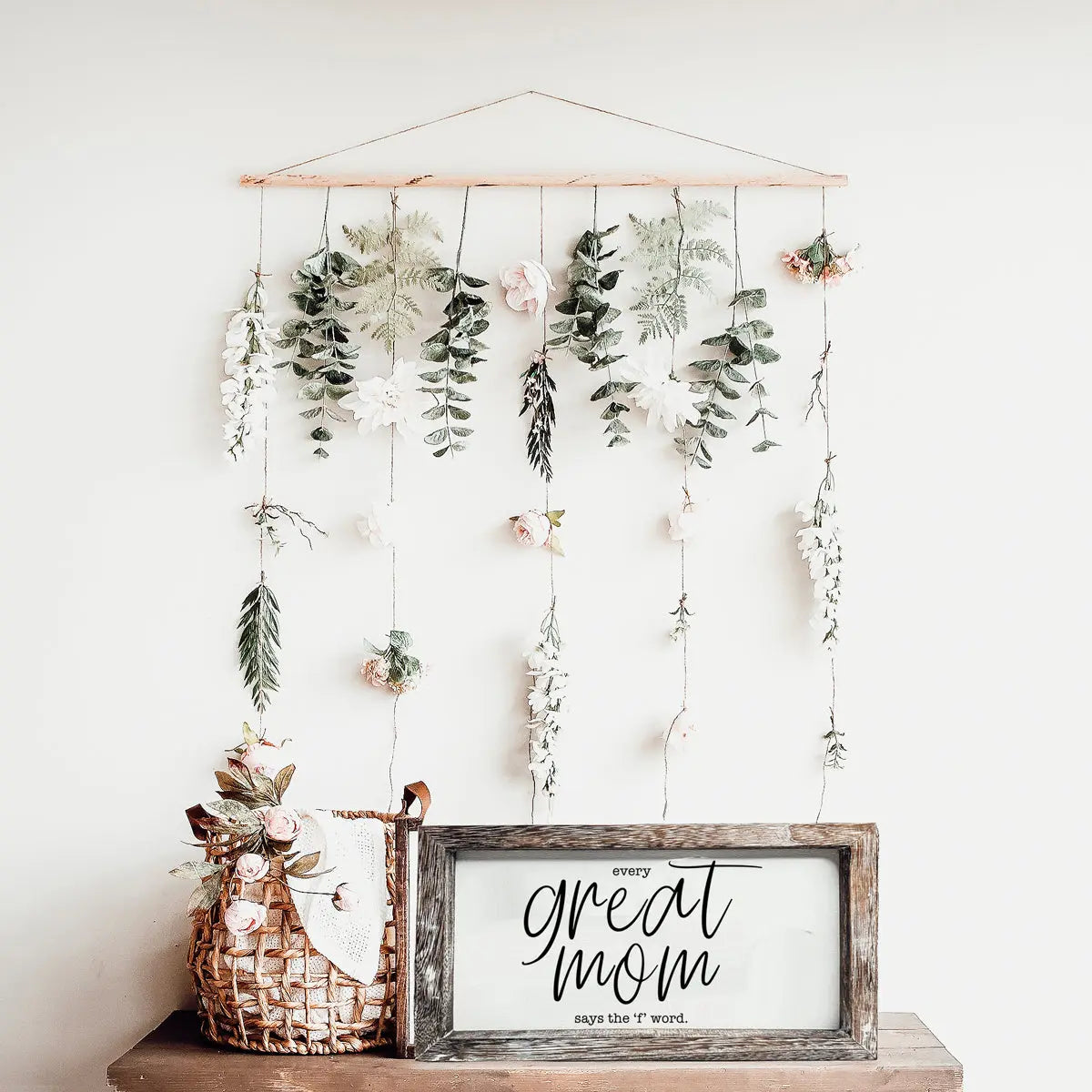 Decorative wall hanging with floral elements and a sign on a white background