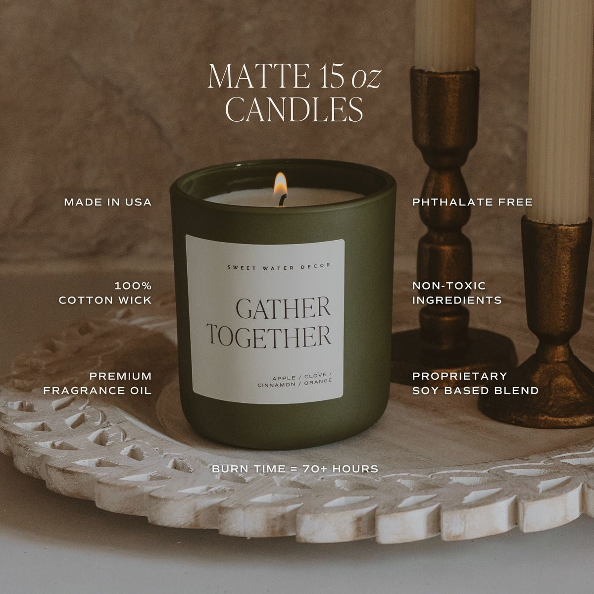 A lit matte 15 oz candle in an olive green jar sits on a carved white tray, with two unlit candles in bronze holders beside it. Text overlays highlight product features such as 'GATHER TOGETHER' scent, 'MADE IN USA,' '100% COTTON WICK,' 'PHTHALATE FREE,' 'NON-TOXIC INGREDIENTS,' and 'BURN TIME = 70+ HOURS.