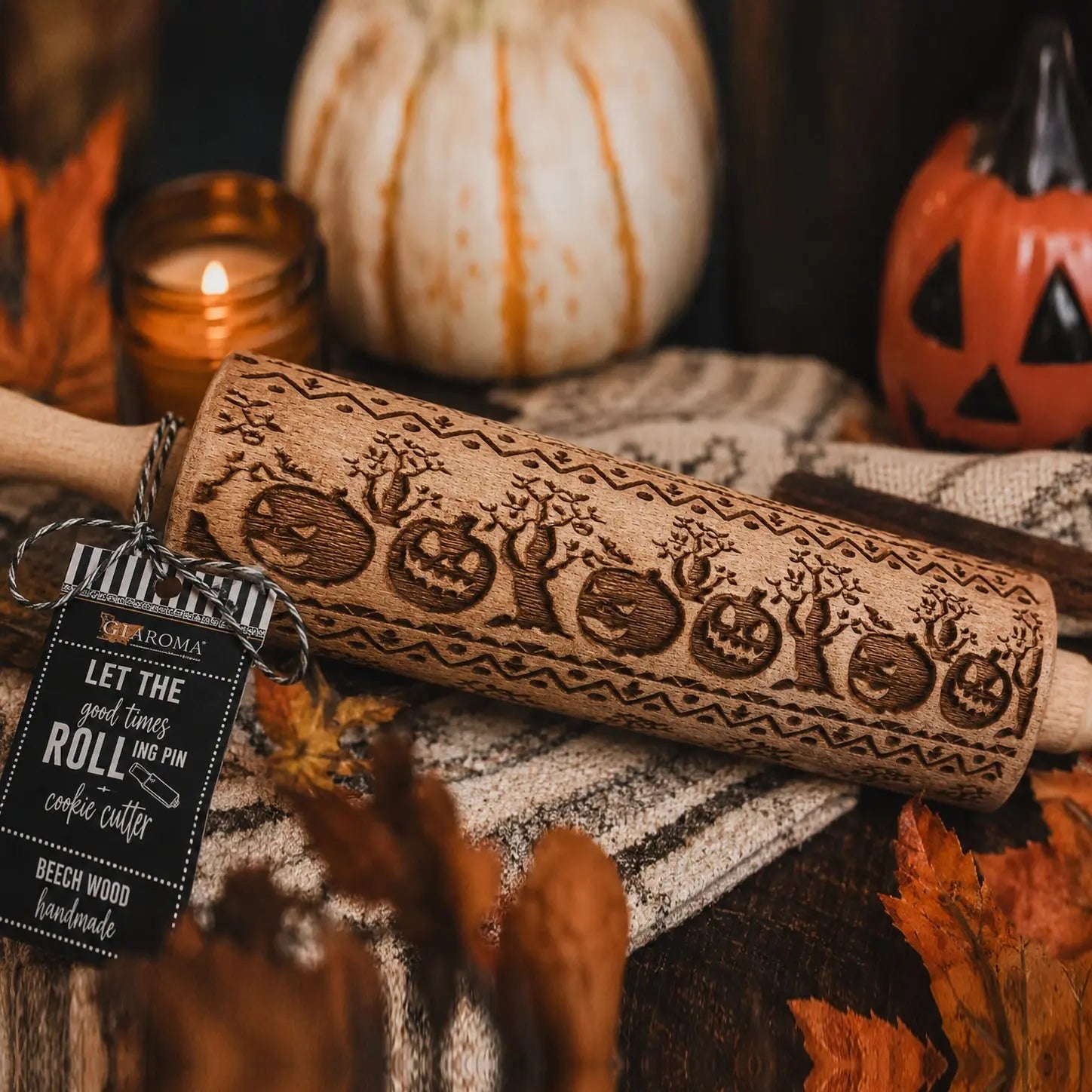 Wooden rolling pin with Halloween designs on a decorative background with pumpkins and candles.
