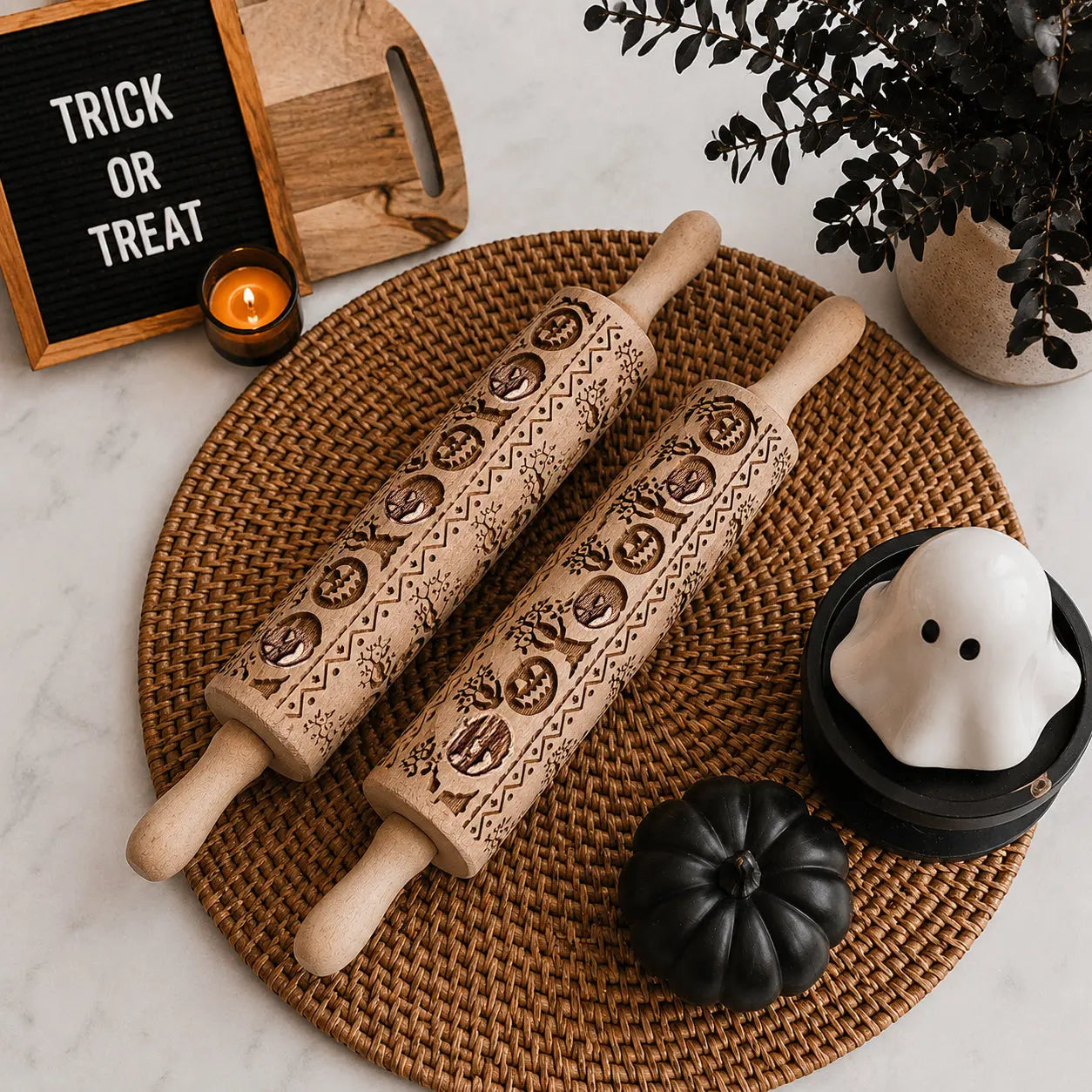 Two Halloween-themed rolling pins on a woven mat with decorative items.