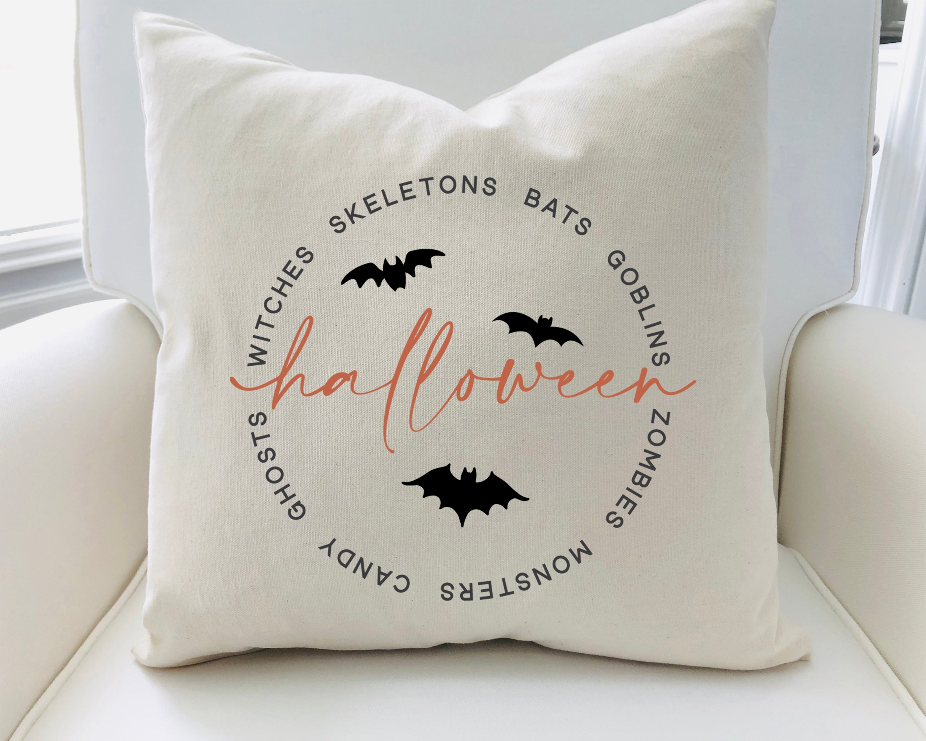 Decorative pillow with Halloween-themed text and bats on a white couch.