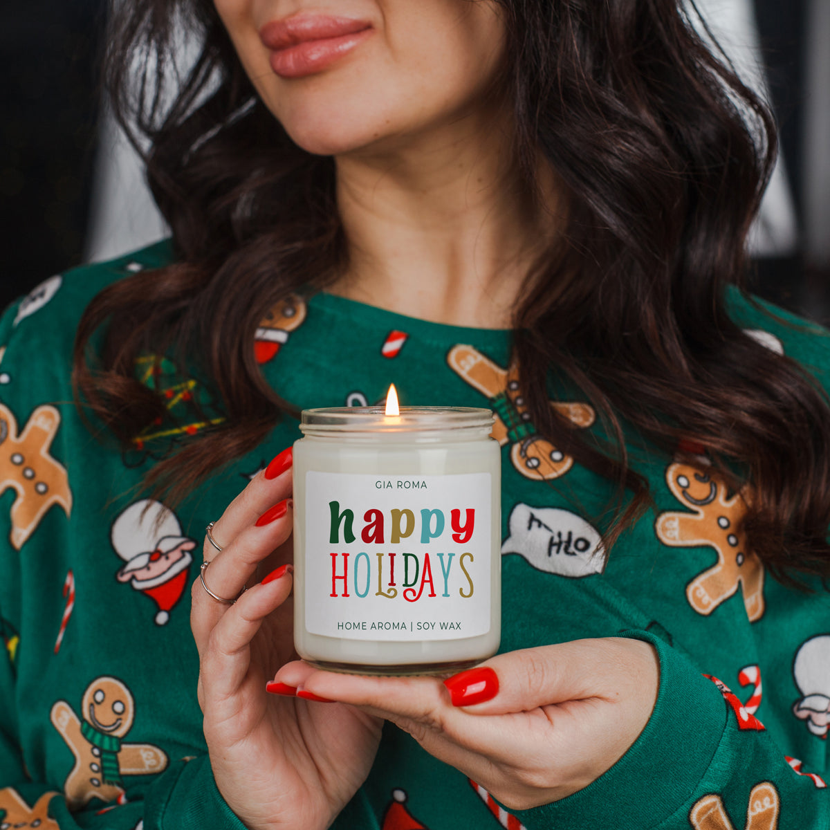 Person holding a 'happy holidays' candle in a festive sweater