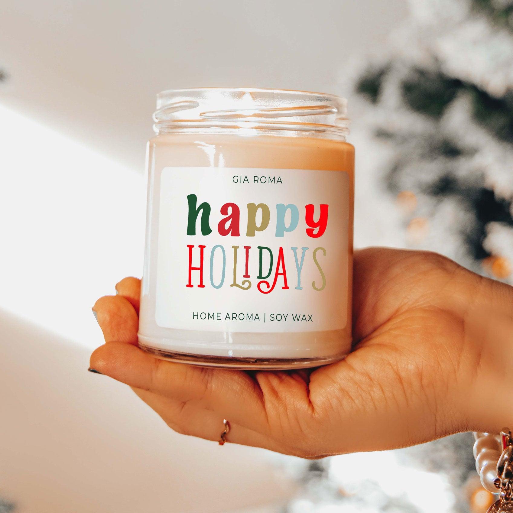Hand holding a 'happy holidays' candle with a blurred background