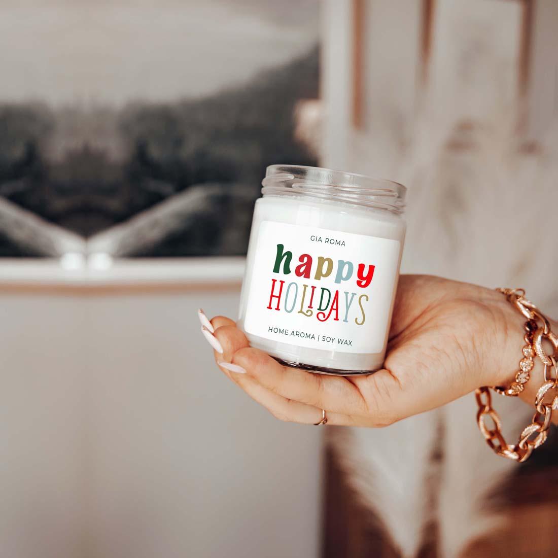 Hand holding a 'happy holidays' candle with a blurred background