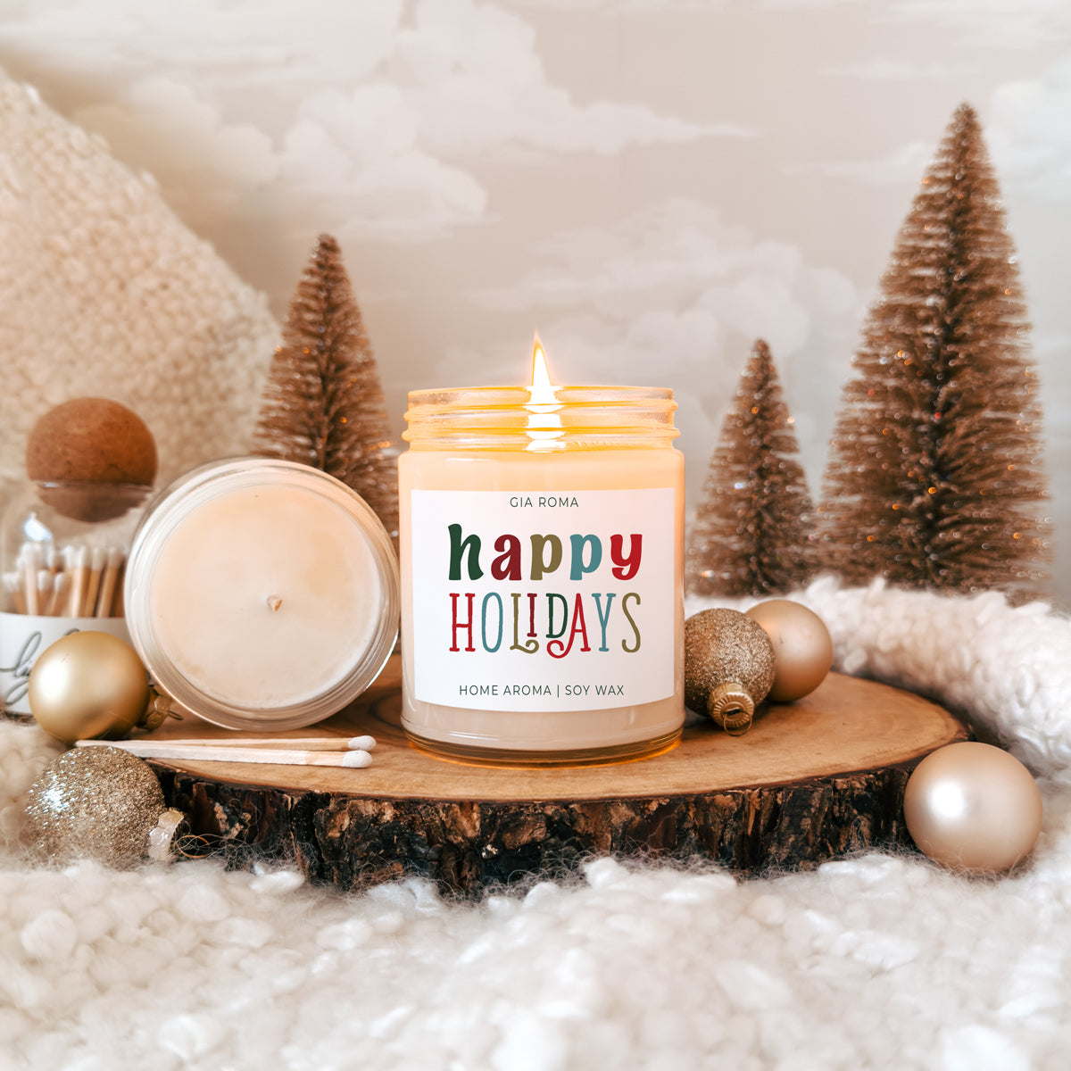Candle with 'Happy Holidays' label on a wooden surface with Christmas decorations.