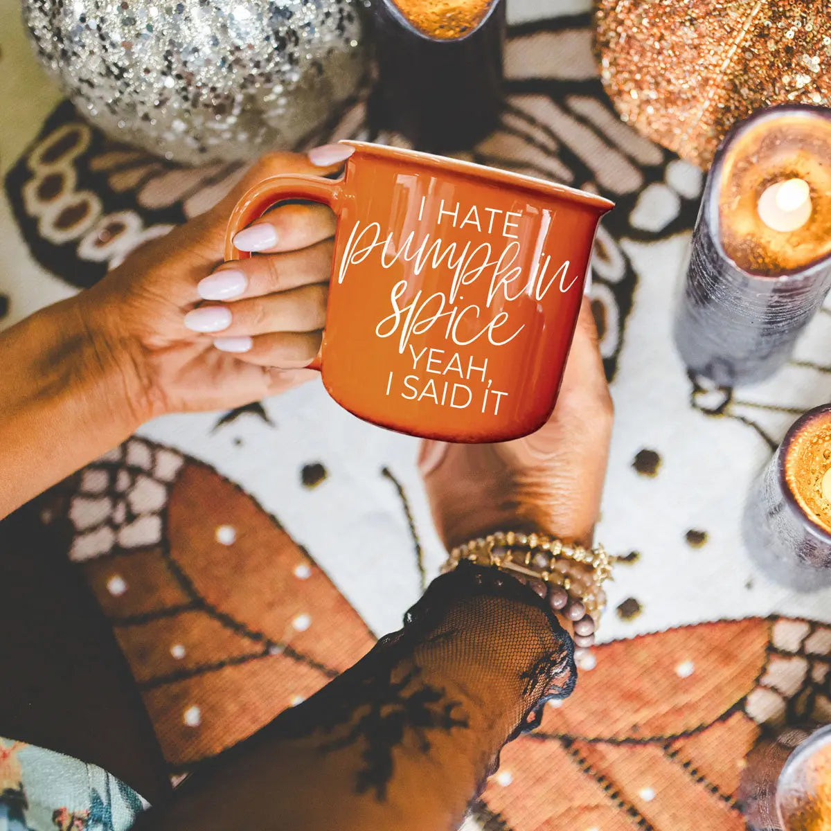 Person holding an orange mug with 'I hate pumpkin spice, yeah, I said it' text on a festive background.