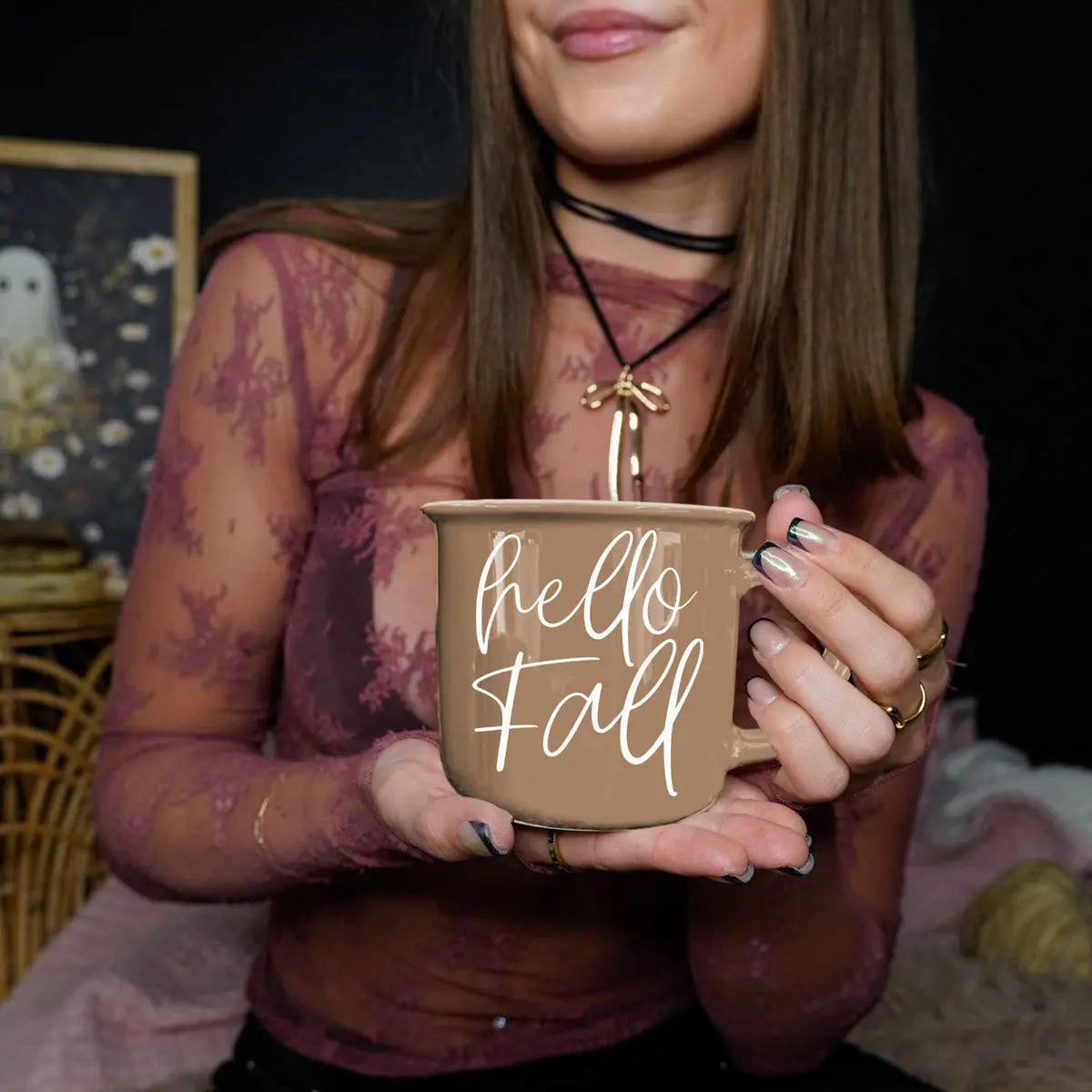 Person holding a 'hello fall' mug with a dark background