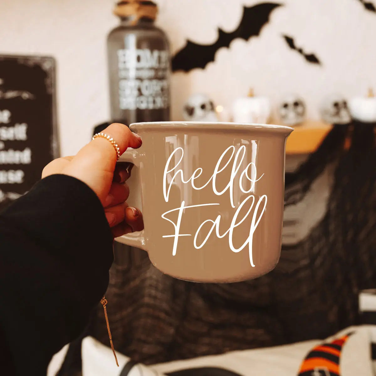 Person holding a mug with 'Fall is my 2nd favorite f-word' text in a Halloween-themed setting.