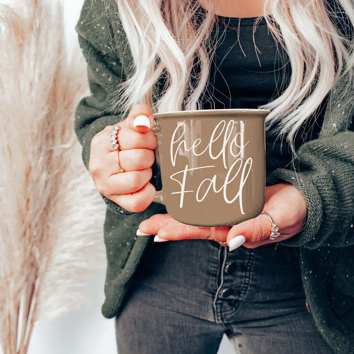 Person holding a 'hello fall' mug with a blurred background