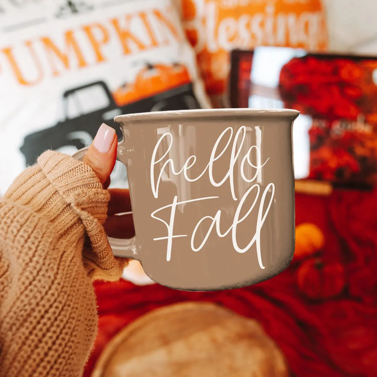 Person holding a 'hello Fall' mug with autumn-themed background