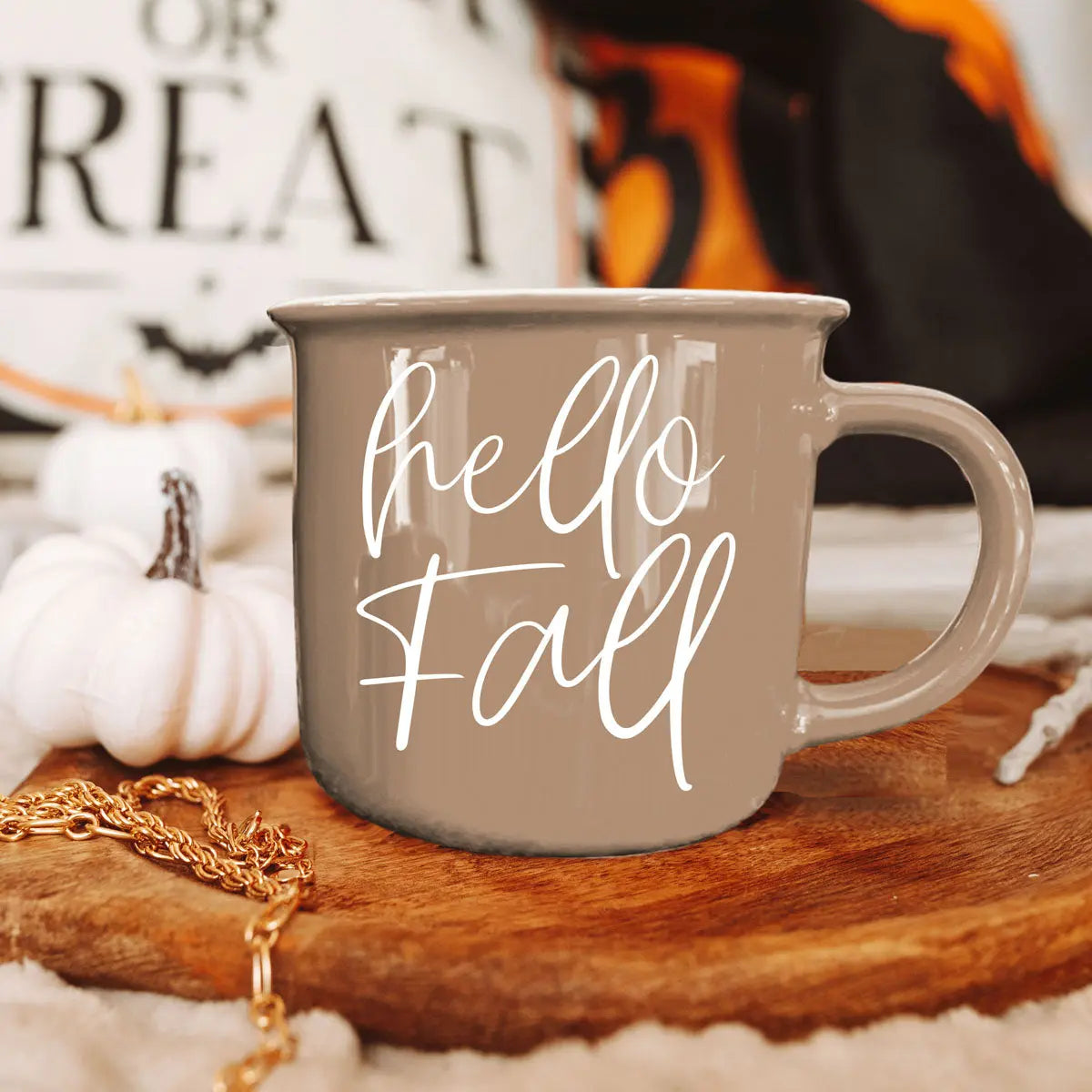 Gray mug with 'hello Fall' text on a wooden surface with pumpkins and decorative items.