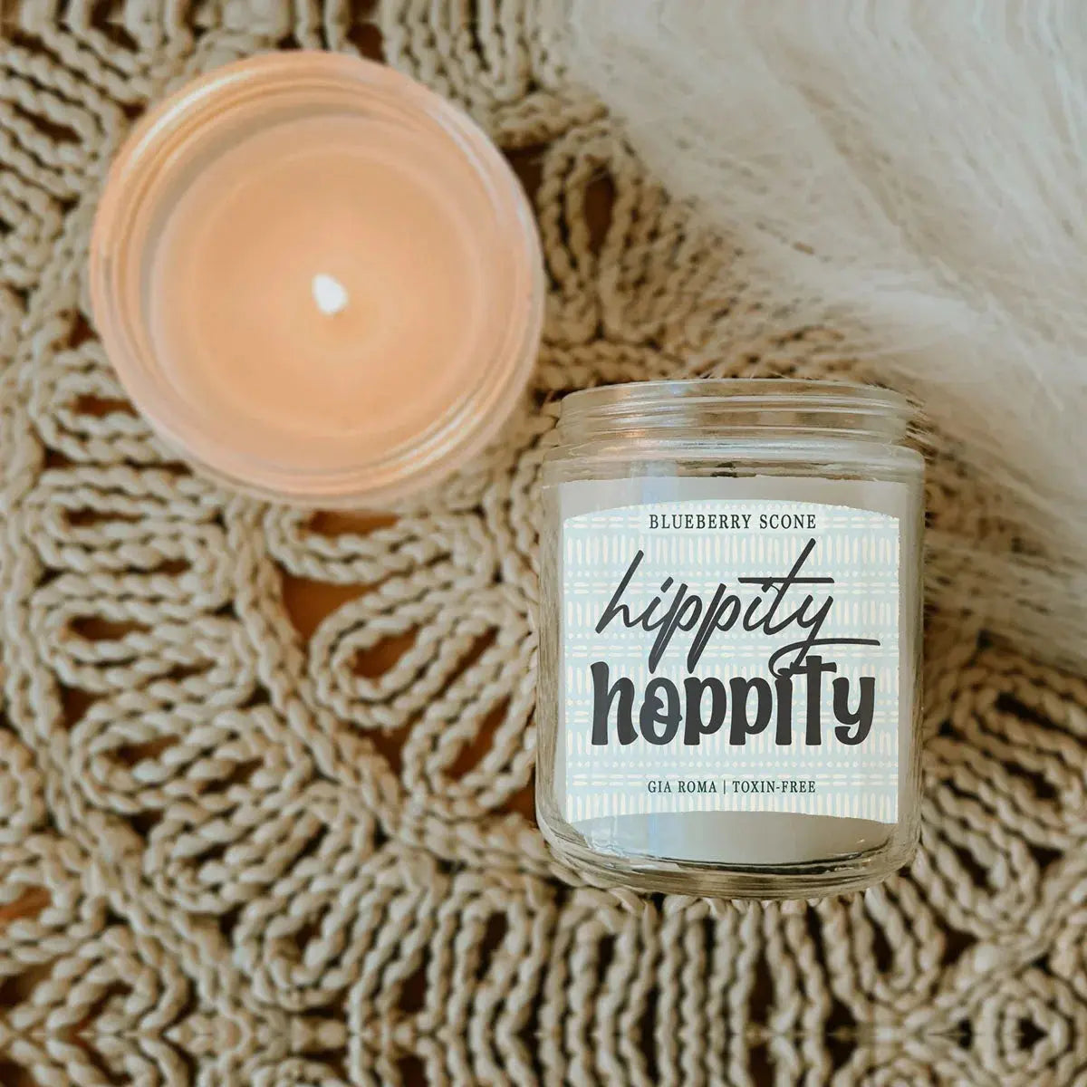 Hippity Hoppity candle jar with a lit candle on a textured surface