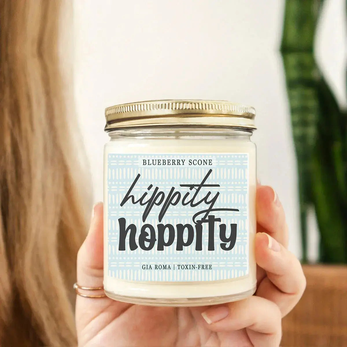 Hand holding a 'hippity hippity' candle with a blueberry scone label.