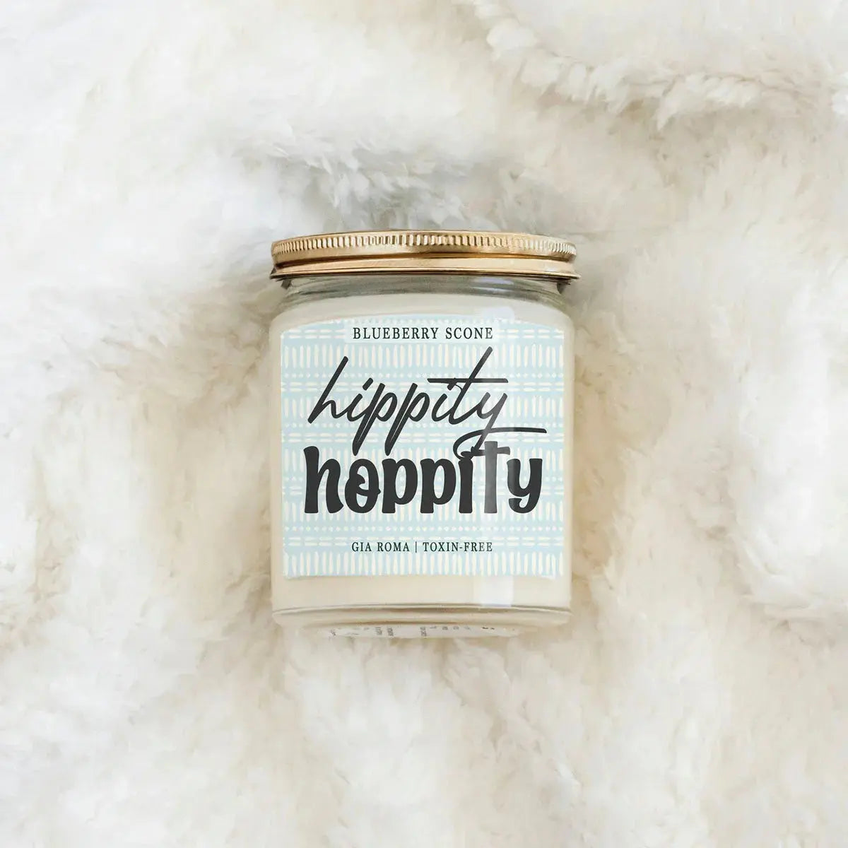 Candle jar labeled 'Hippity Hoppity' on a fluffy white surface