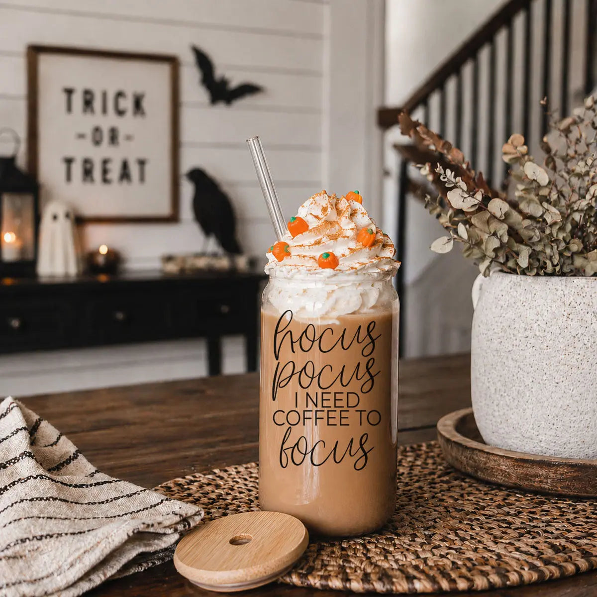 Halloween-themed drink with whipped cream and candy on a table, decorated for Halloween.