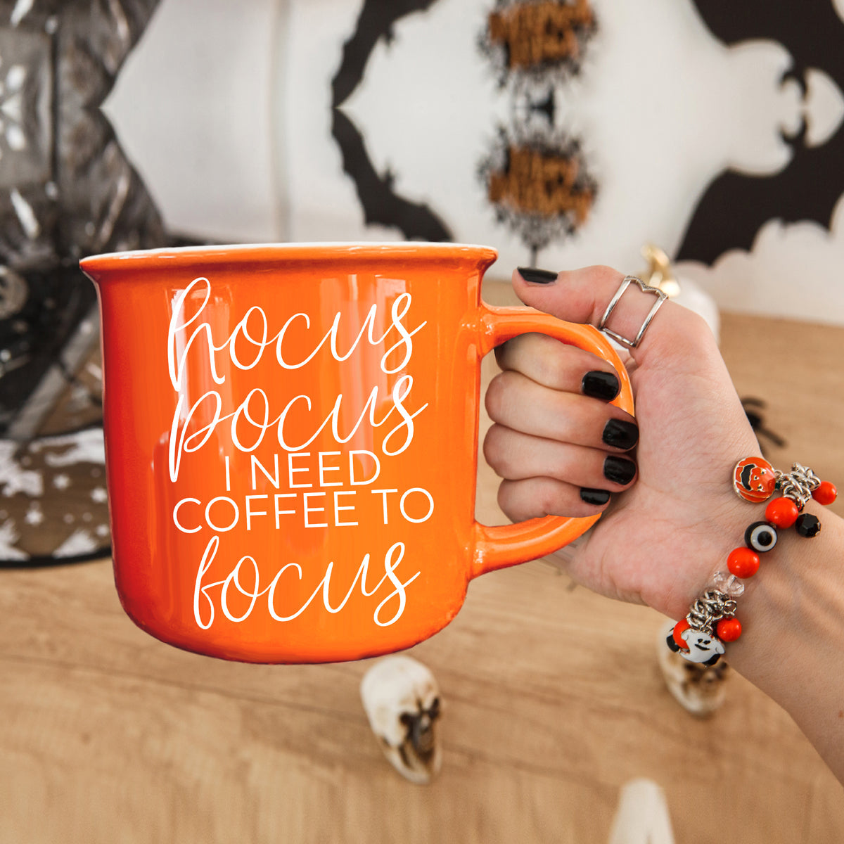Orange mug with text held by a hand, with a blurred background