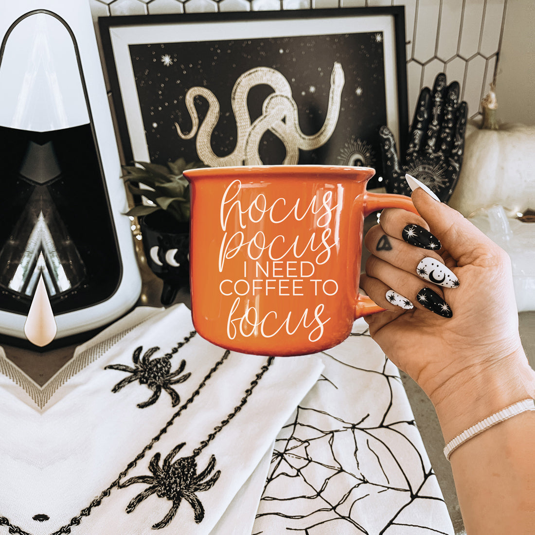 Orange mug with 'I hate pumpkin spice, yeah, said it' text held by a hand in a Halloween-themed room.