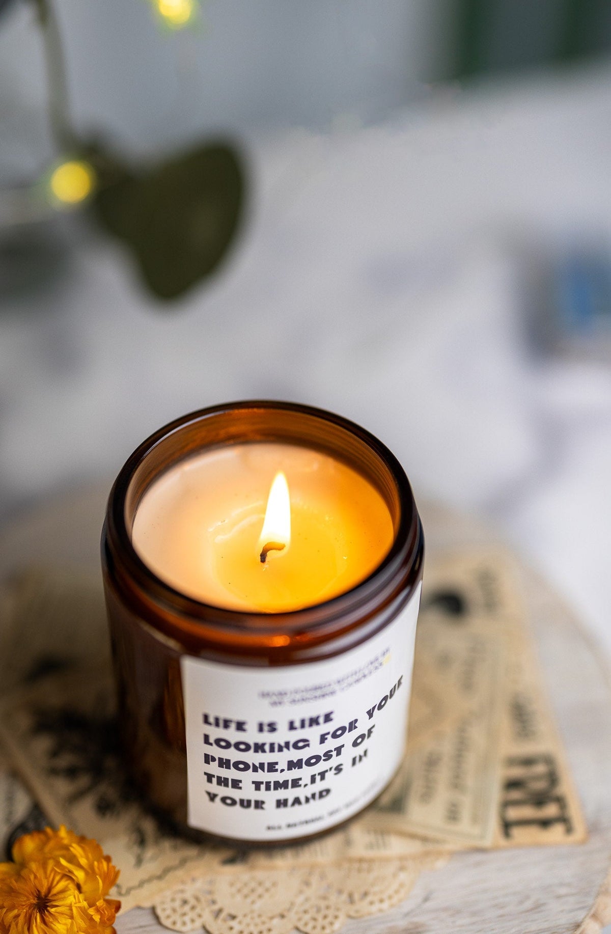 A lit amber glass jar candle with a white label that reads, 'LIFE IS LIKE LOOKING FOR YOUR PROVE.