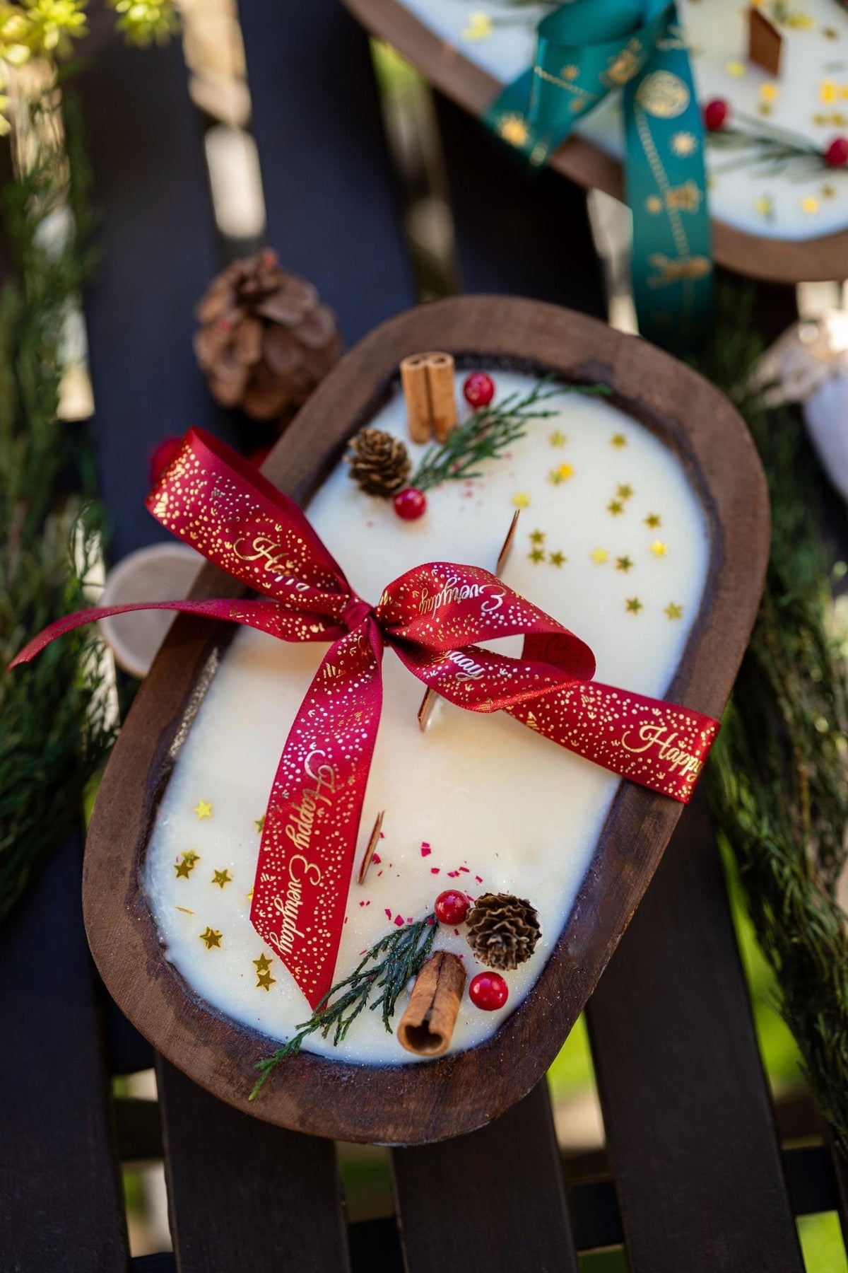 Decorative candle shaped like a gingerbread man with a red ribbon, surrounded by Christmas decorations.