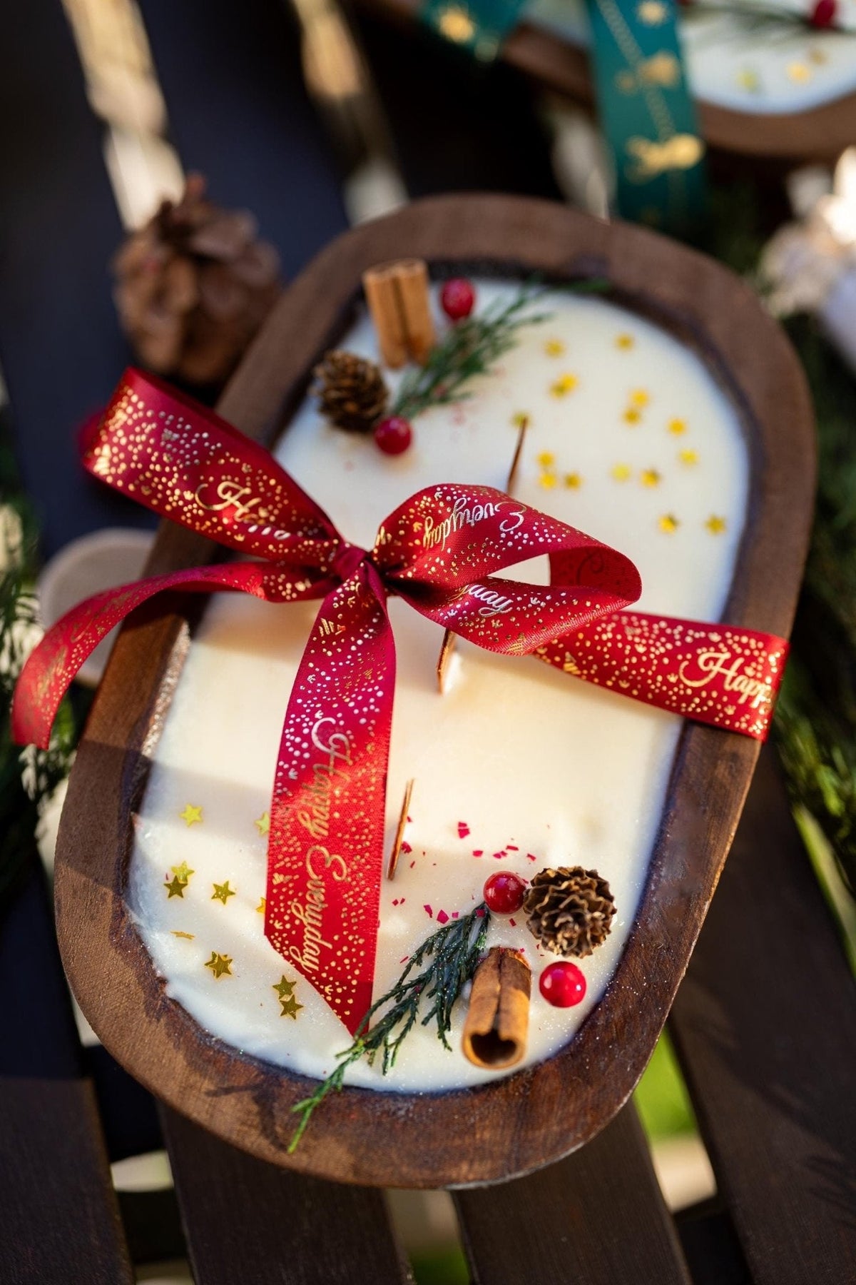 Decorative candle in a wooden sleigh with a red ribbon, pine cones, and cinnamon sticks.
