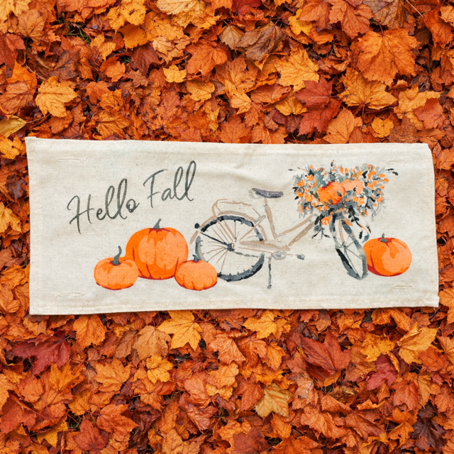 Decorative mat with 'Hello Fall' text and pumpkins on a bed of autumn leaves