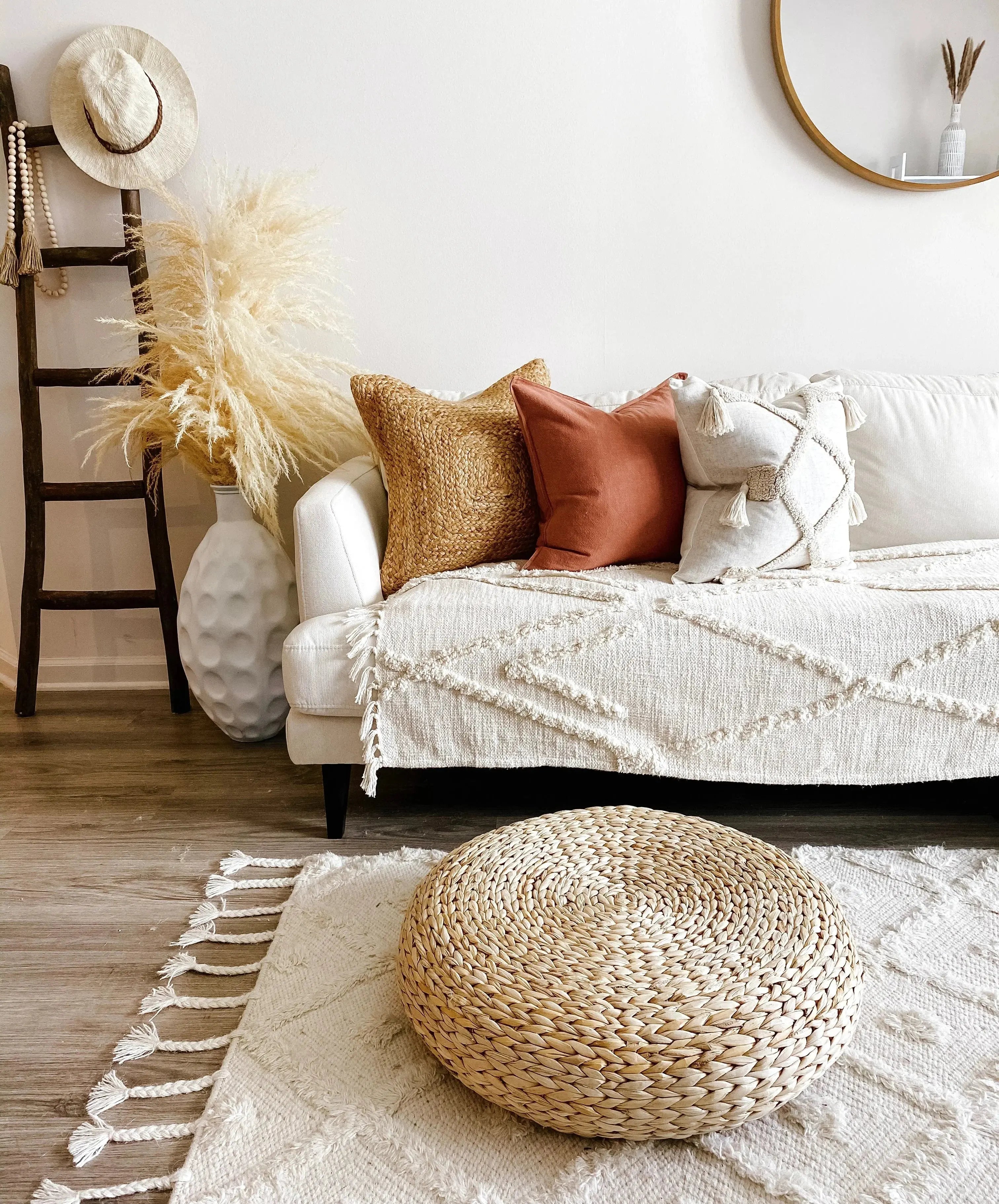 Cozy farmhouse living room with woven pouf, textured throw pillows, and rustic decor accents