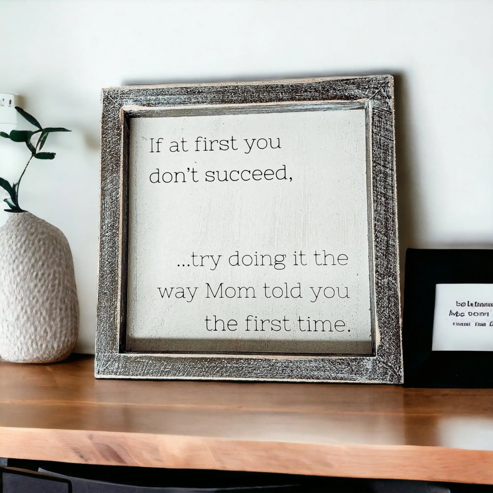 Framed motivational quote on a wooden surface with decorative elements.