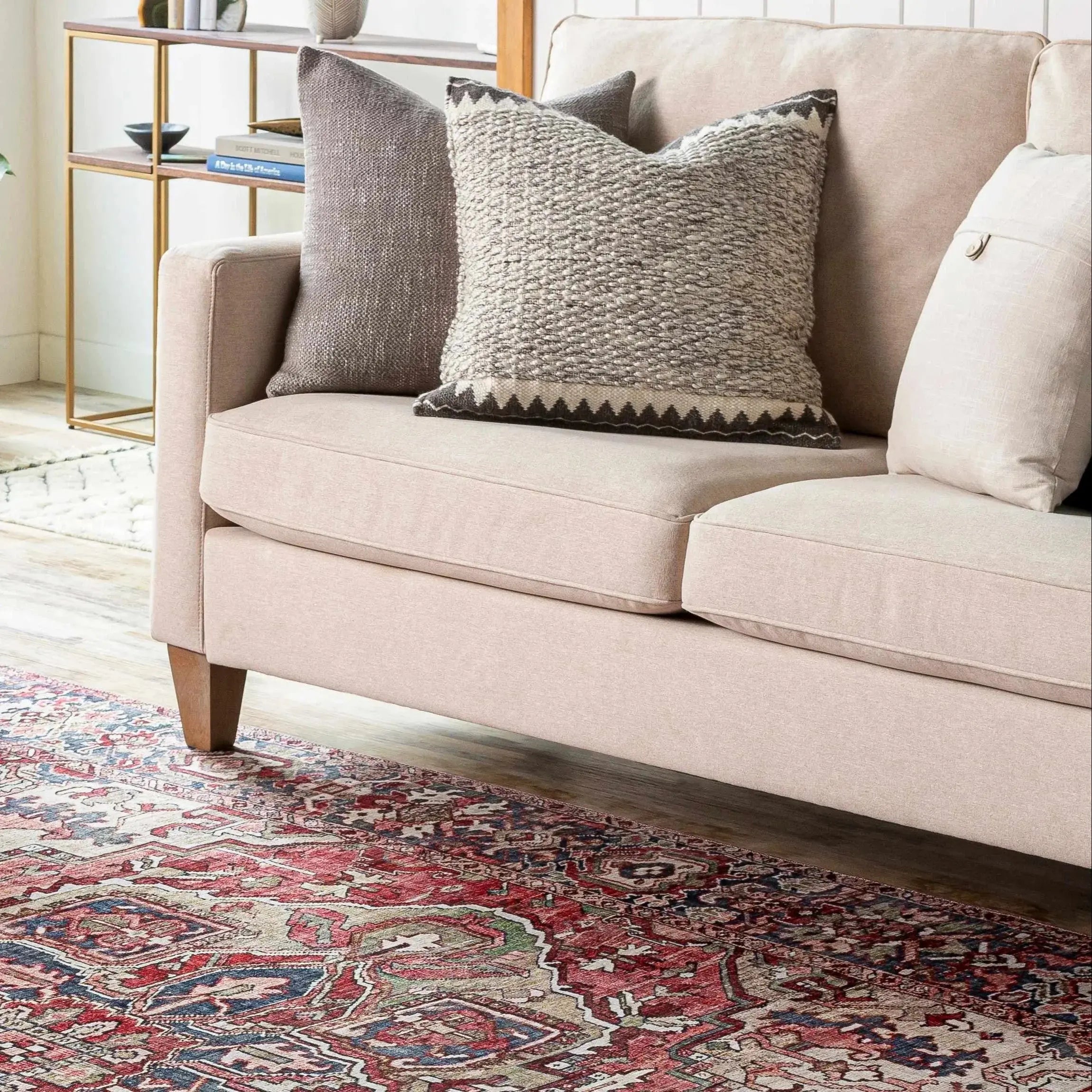 Beige farmhouse sofa with textured throw pillows on vintage rug, cozy living room decor