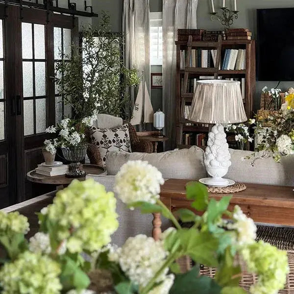 Cozy farmhouse living room with white hydrangeas, rustic wood furniture, and soft neutral decor