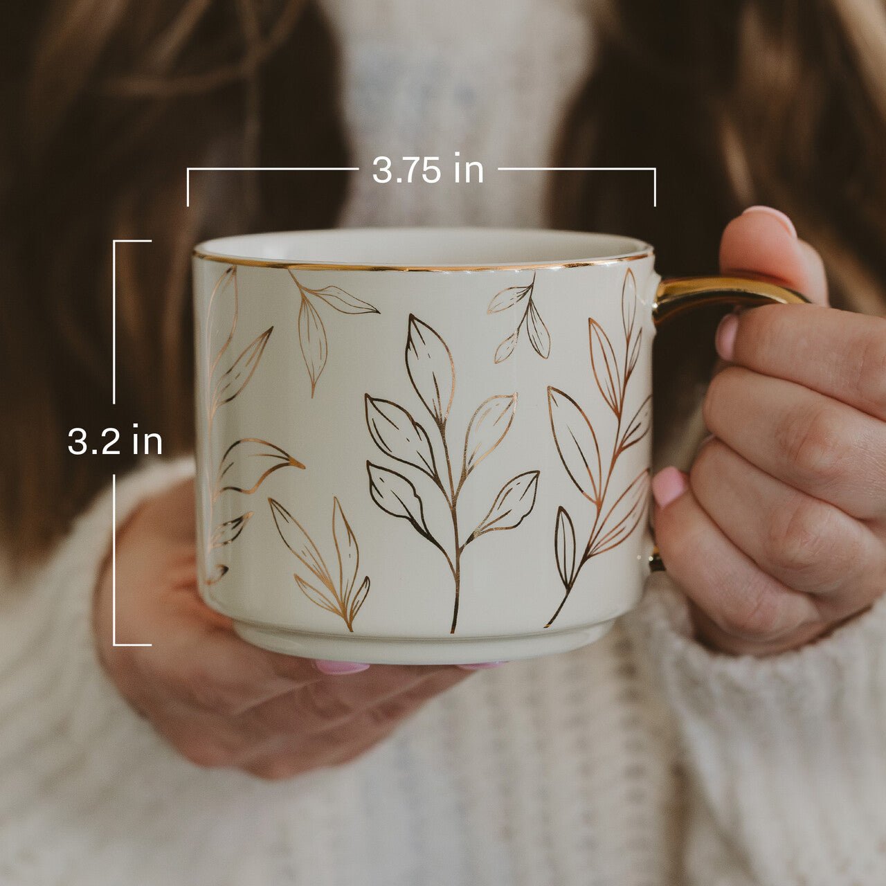 Person holding a mug with leaf pattern and measurements