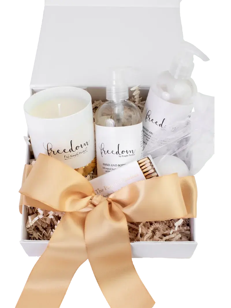 Freedom-themed self-care gift set with candle, hand & body spray, and bath essentials in white box with gold bow