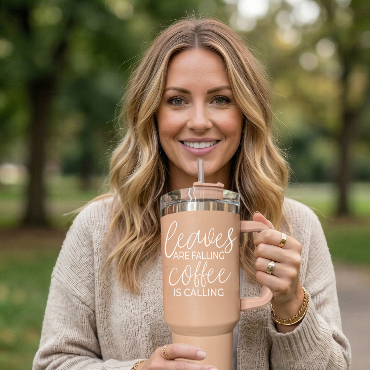 Woman holding a pink insulated tumbler with text in a park