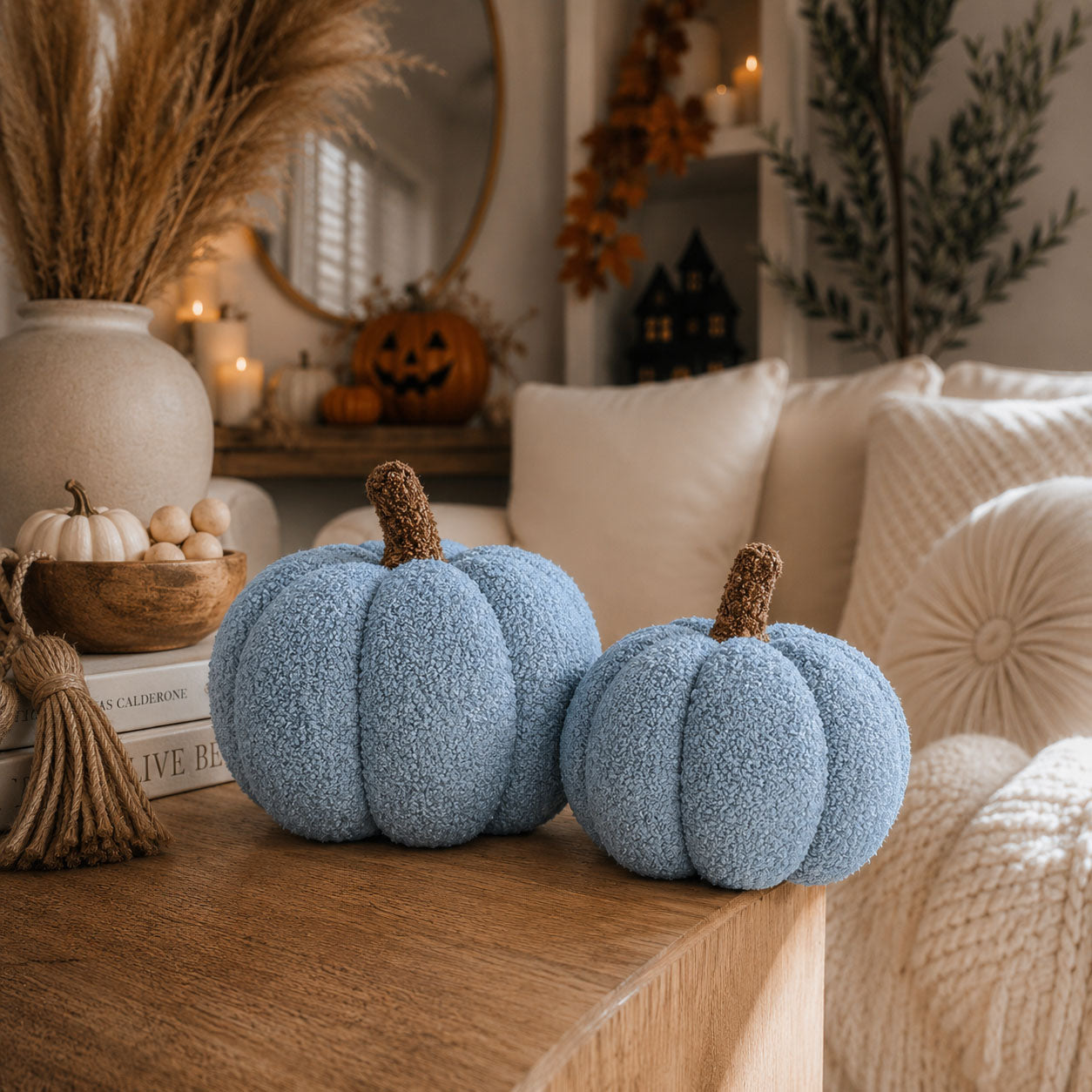 Two blue textured pumpkins on a wooden surface with a cozy living room background.