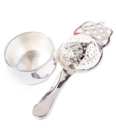 Silver tea strainer with decorative handle and matching cup, farmhouse kitchen accessory